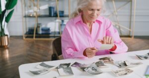 Grandma's Answer About Her Happiest Memory Left Her Family Speechless A senior woman reliving past memories by looking through old photographs at a table.