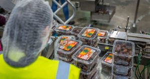 You Should Never Eat 13 Foods After They Expire, According to Experts Worker managing date packaging in a modern industrial facility, ensuring quality control.