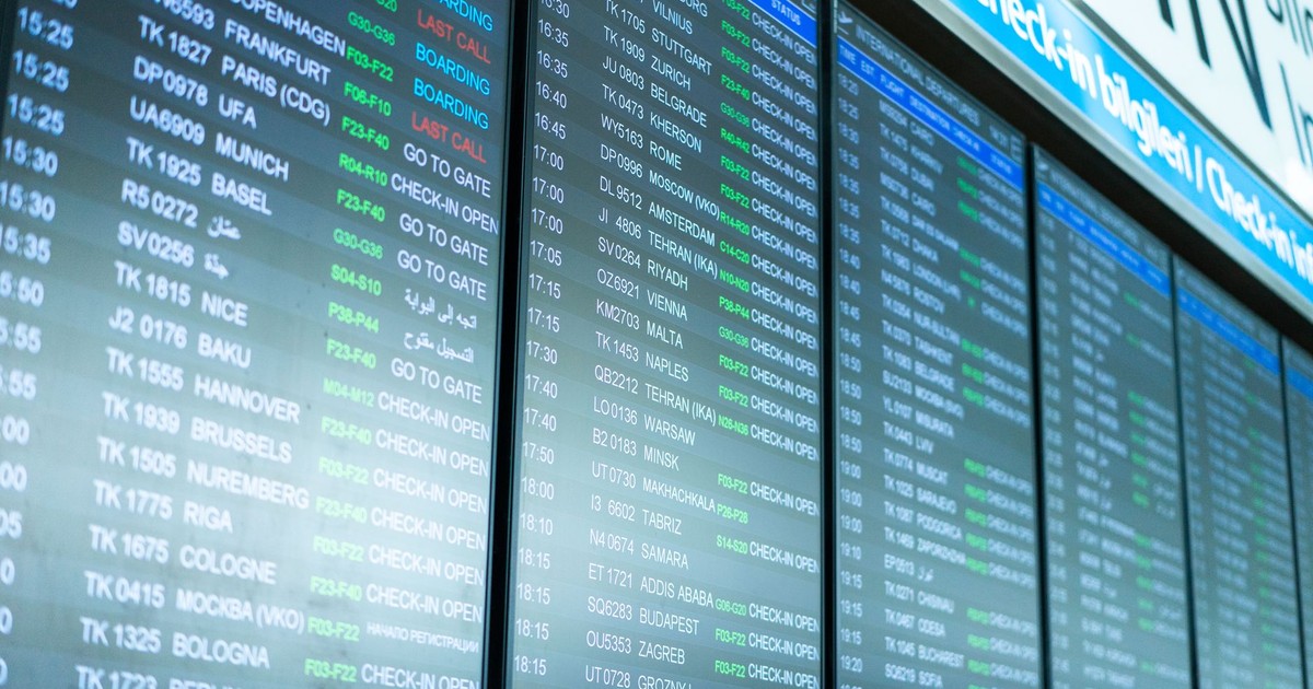 Digital screens display flight information and schedules at an airport terminal.