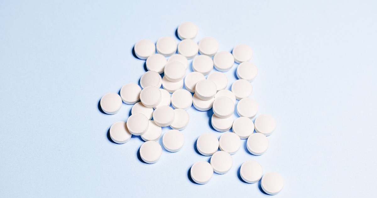 A collection of white tablets scattered on a light blue surface, perfect for health-related content.