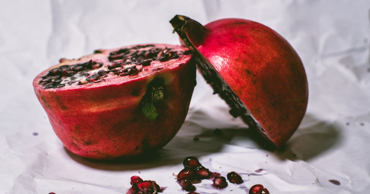 Close-up of fresh pomegranate halves on paper, highlighting vibrant seeds.