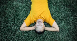 12 Simple Things That Genuinely Make Men Happy A man in a yellow shirt relaxing on green grass, enjoying a peaceful moment.