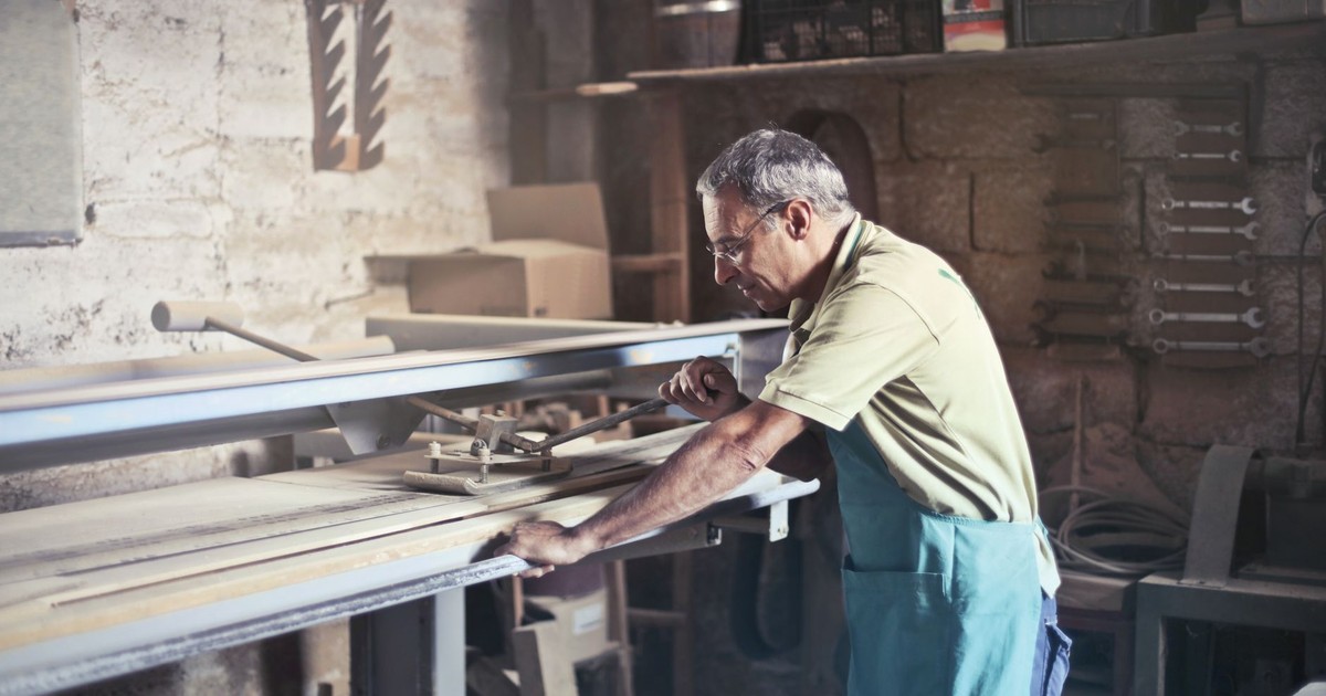 An artisan focuses on woodworking in a rustic indoor workshop, showcasing craftsmanship.
