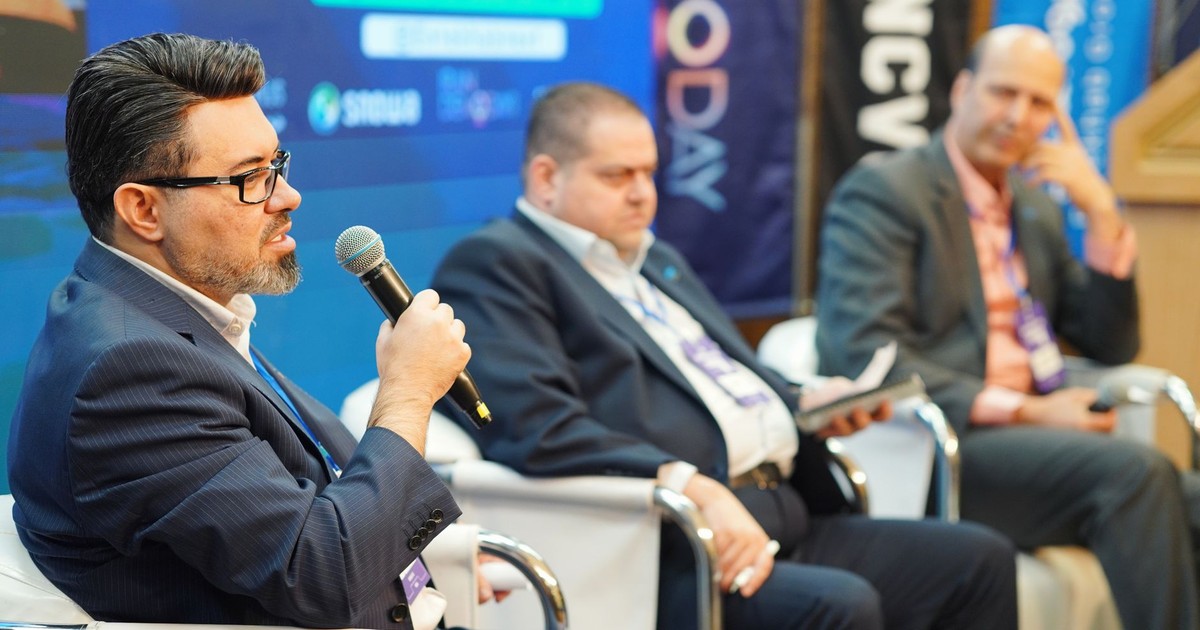 Three men engaged in a panel discussion at a professional conference.