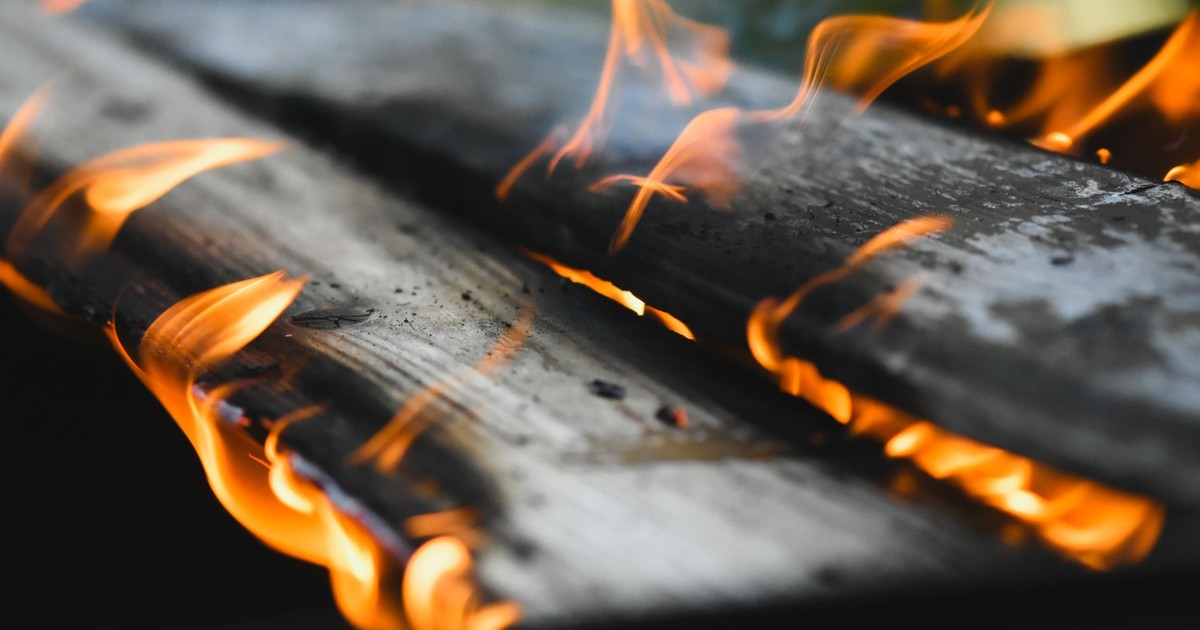Vivid flames engulf wooden planks in an outdoor fire setting, showcasing warmth and energy.