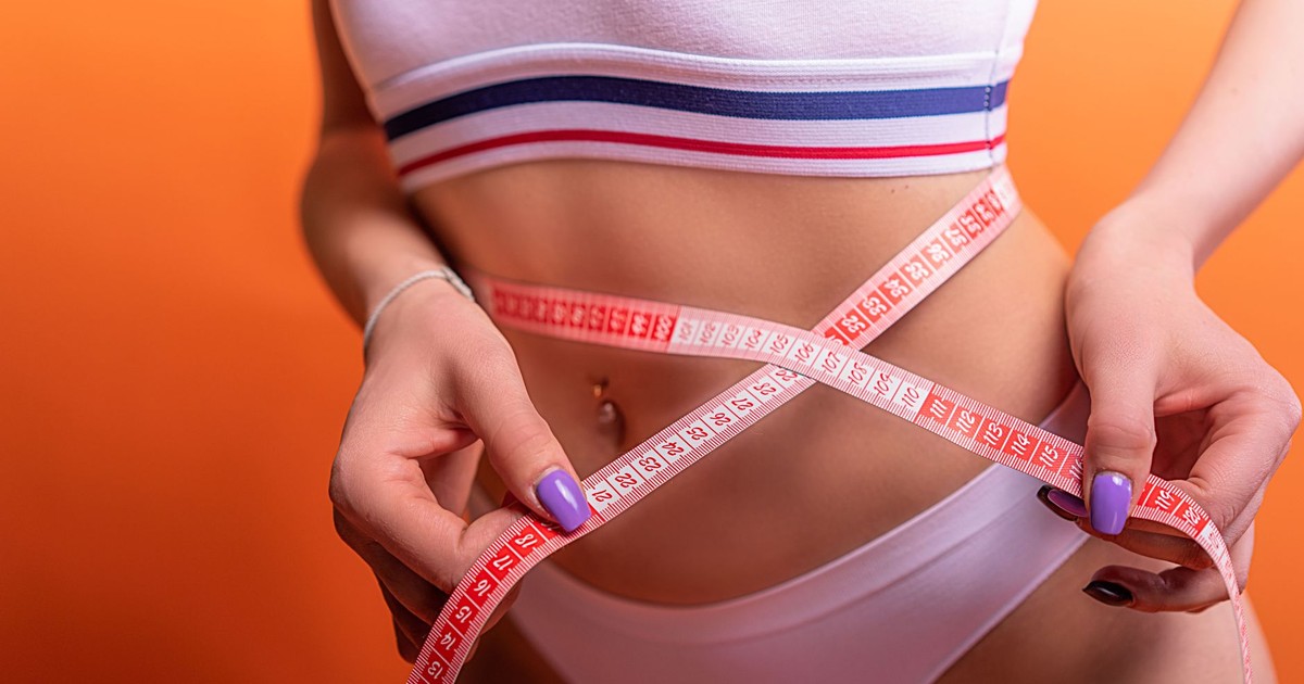 Close-up of a woman in underwear measuring her waist with a tape measure, fitness concept.