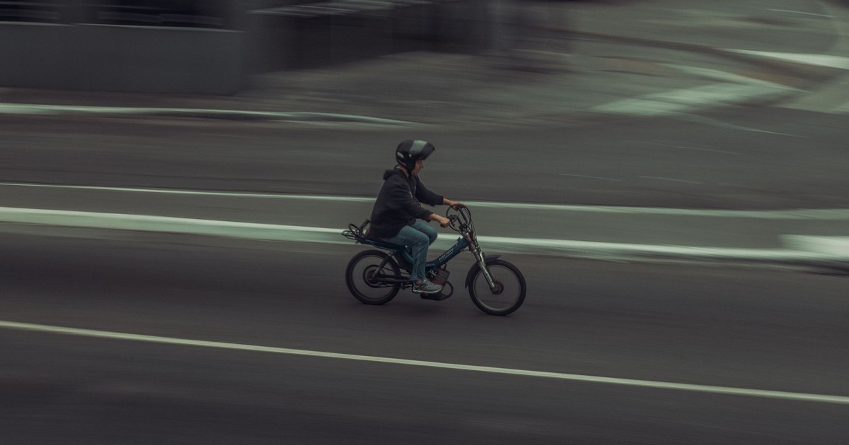 A person riding a bicycle at high speed on a city street, captured with motion blur effect.
