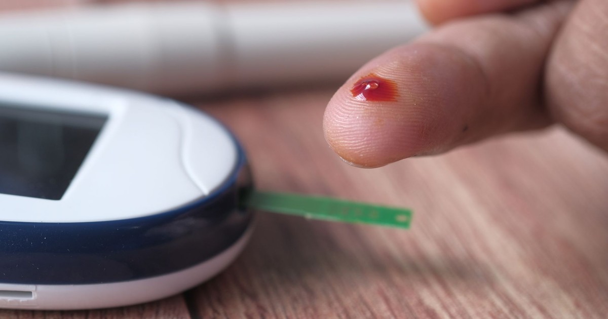 A close-up of a finger prick and blood glucose monitor for diabetes testing.