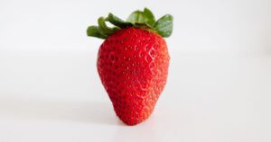 How Fructose May Be Wrecking Your Brain, Liver, and Waistline A single fresh strawberry on a white background, perfect for food photography stock.