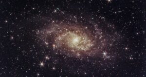 Bright spiral galaxy surrounded by stars in deep space.