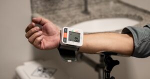 9 Prehypertension Signs Most People Don't Recognize Until It's Too Late Close-up of an arm using a wrist sphygmomanometer in a healthcare setting.