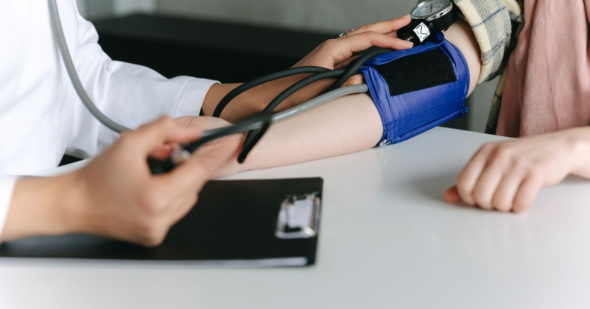 A healthcare worker uses a sphygmomanometer to check a patient's blood pressure in a medical office.
