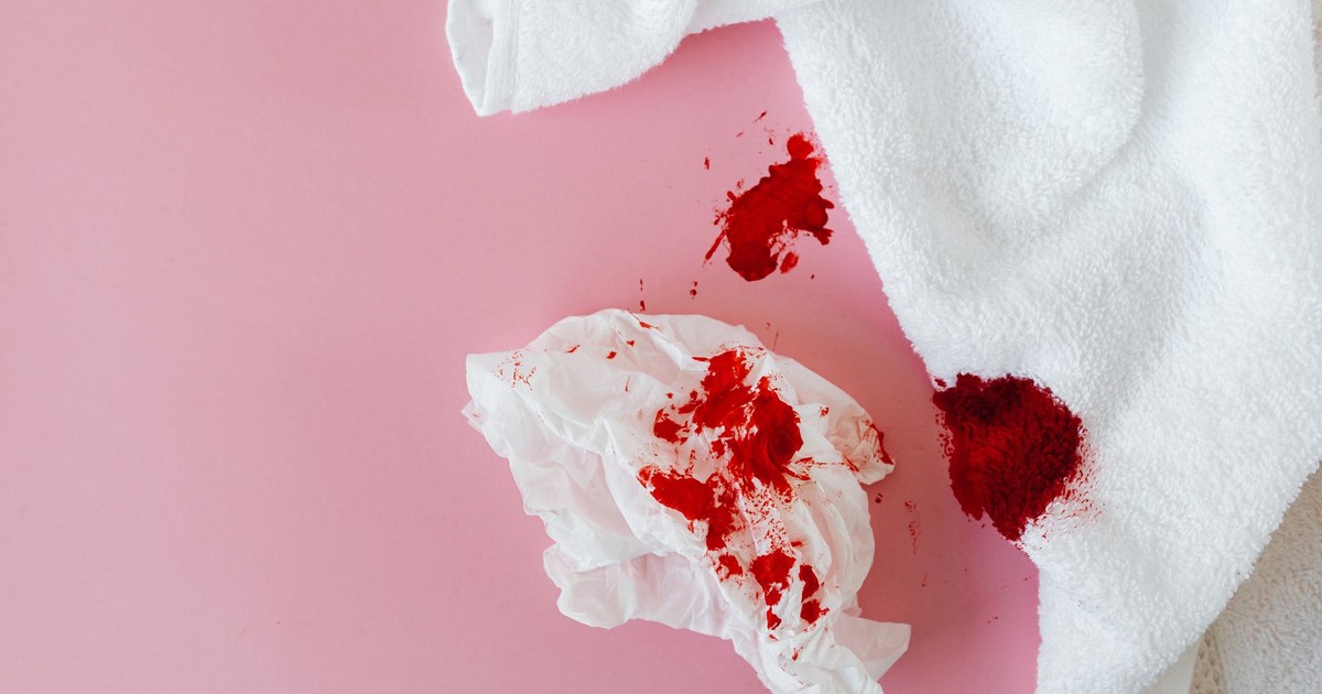 Close-up image showing menstrual stains on a towel and tissue on pink background.