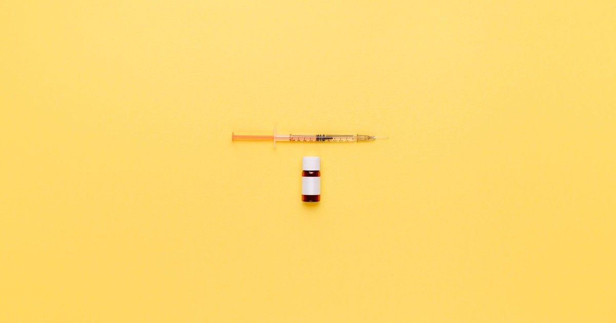Minimalist image of a syringe and vaccine vial on a vibrant yellow background.