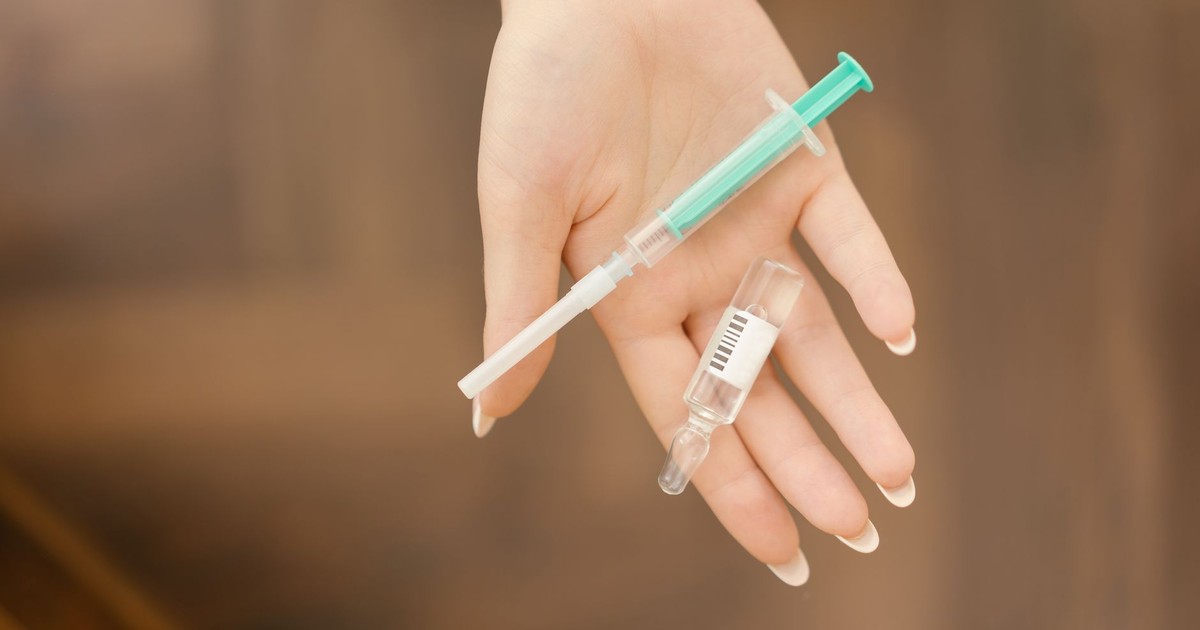 A close-up of a hand holding a medical syringe and vial, symbolizing healthcare or vaccination.