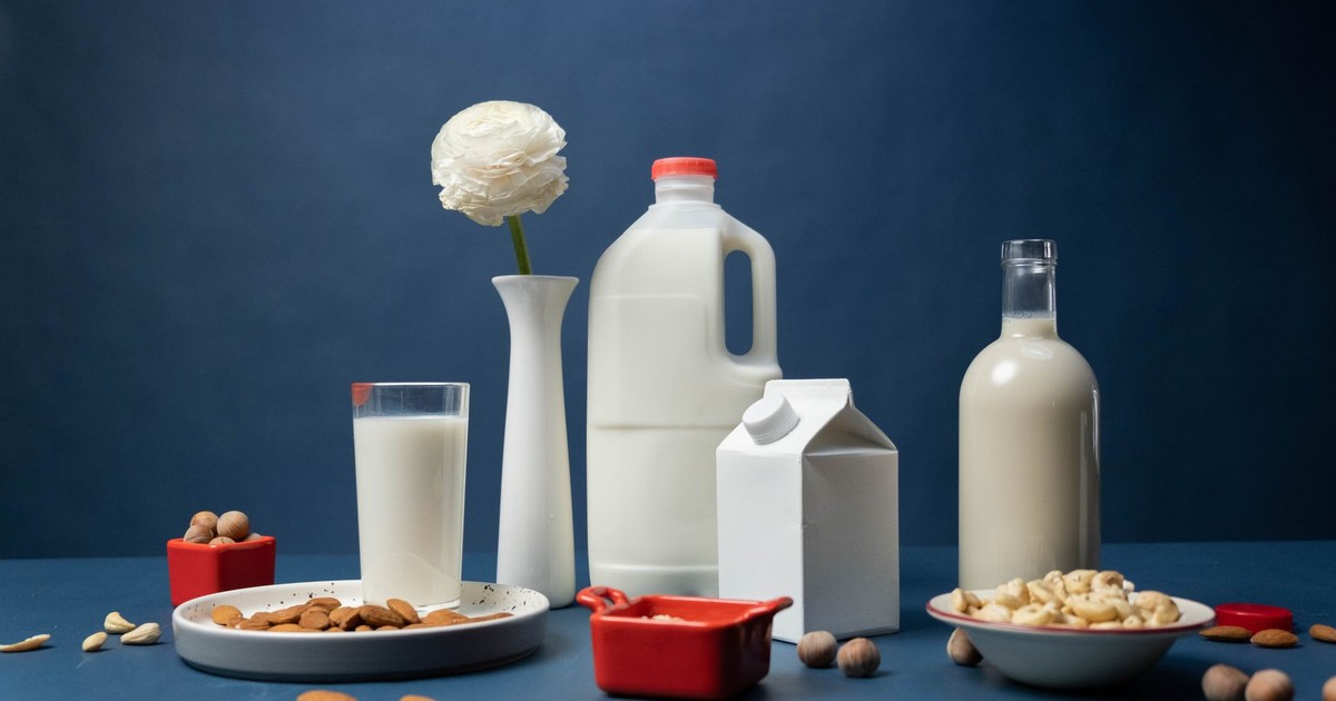 Still life of assorted vegan nut milks with nuts and decorative flower in studio.