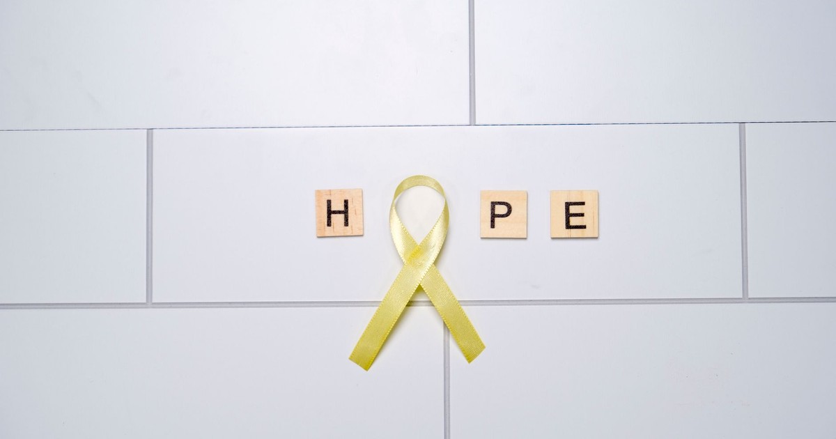 A yellow ribbon forming the word 'hope' with tiles on a white tiled background, symbolizing awareness and support.