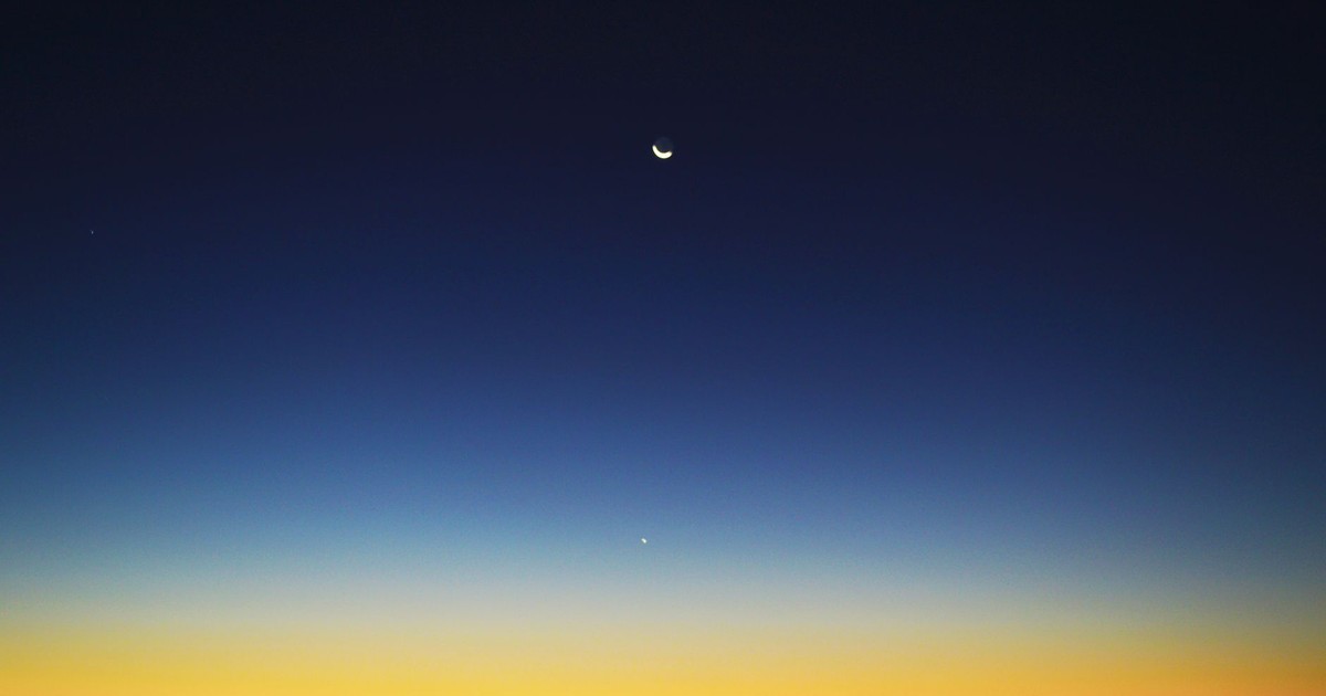 Crescent moon and planet visible in a colorful twilight sky over Mahajanga, Madagascar.