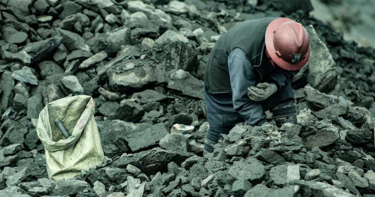 A woman mining for gold in La Rinconada, Peru, surrounded by rocks and debris.