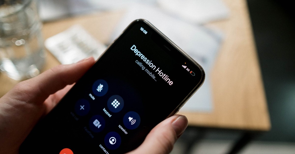 Close-up of a person holding a smartphone, calling a depression hotline.