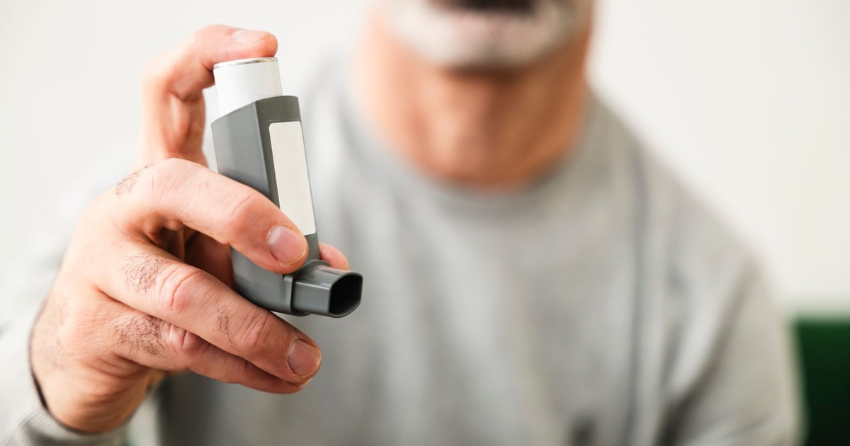 Man using an inhaler for respiratory health indoors.