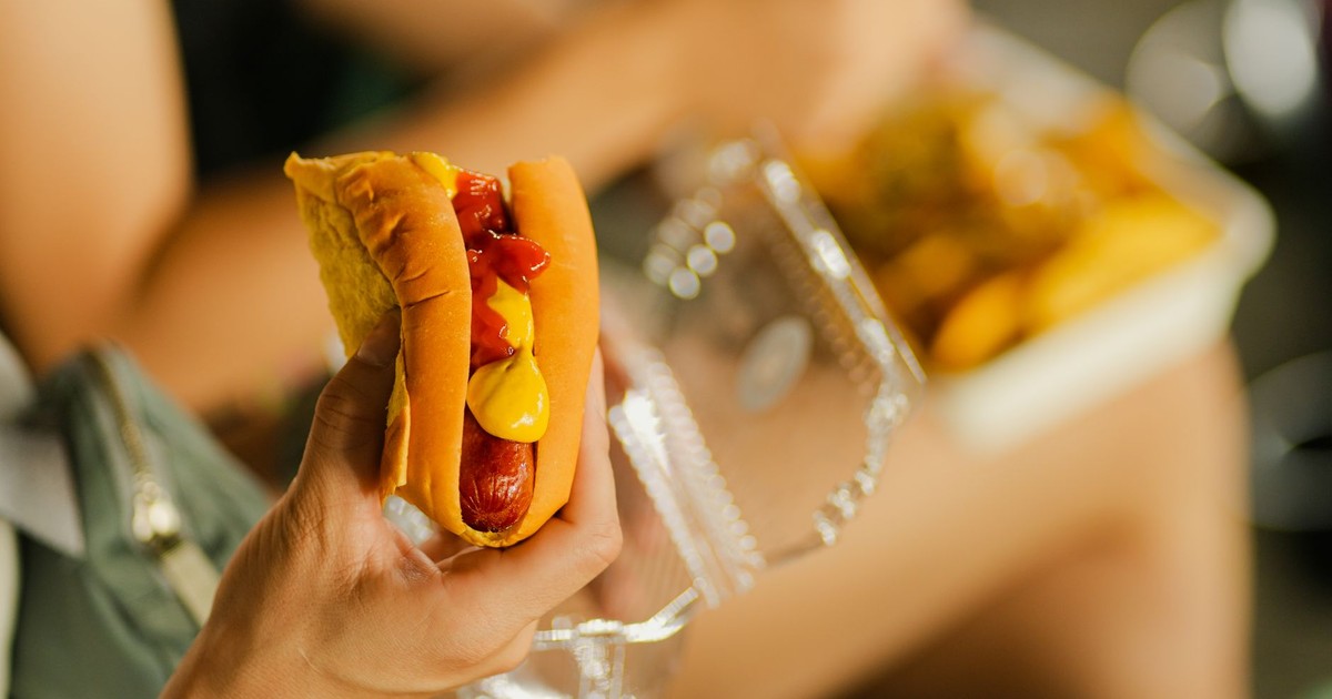 Close-up of a hot dog with mustard and ketchup held in hand, perfect street food meal.