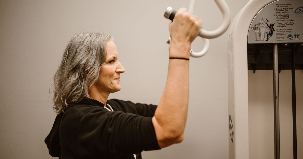 Active senior woman working out on gym equipment, focusing on strength and wellness.