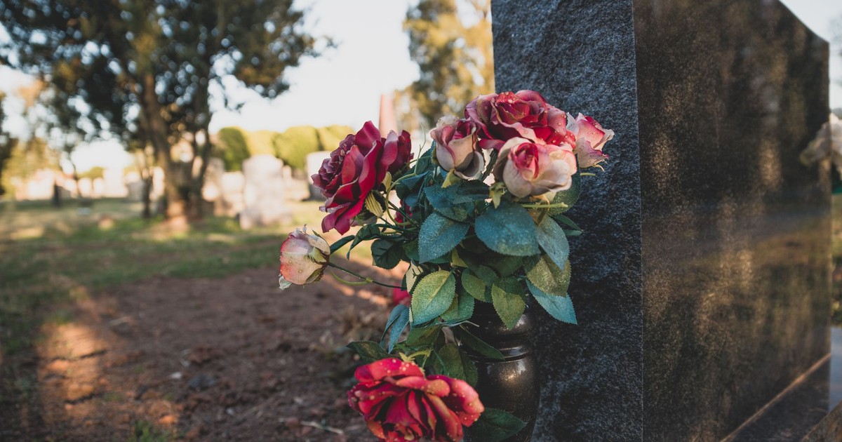 Close-up of roses on a gravestone in a serene cemetery setting.