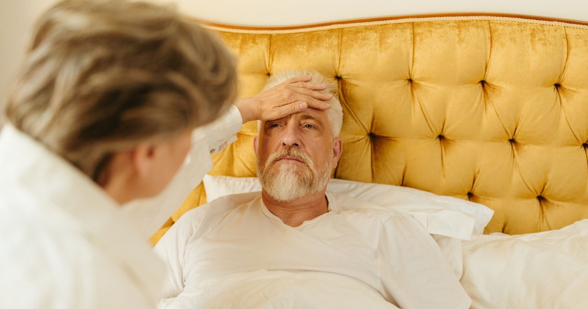 Elderly man in bed receiving care from a woman at home.