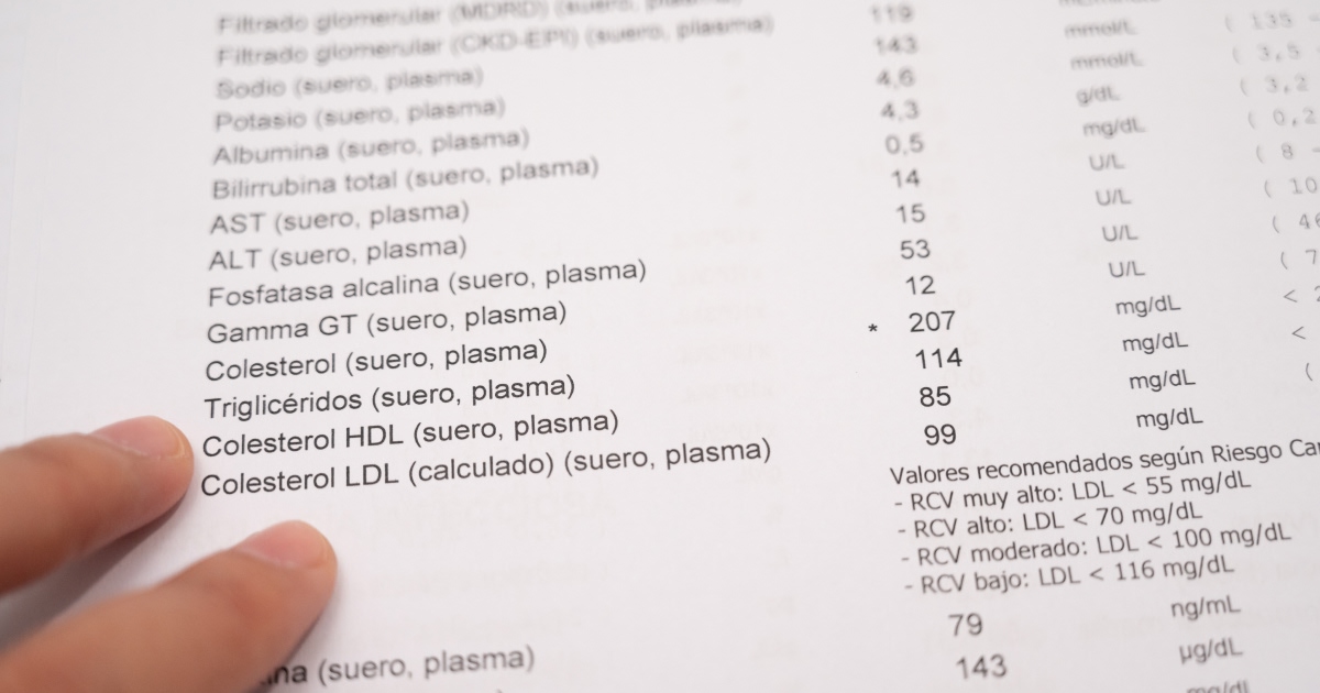 Finger pointing at blood test results, showing cholesterol levels on a Spanish medical report