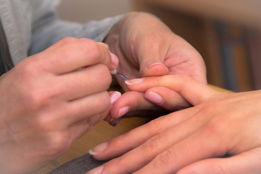 A manicurist painting someone's nails. 