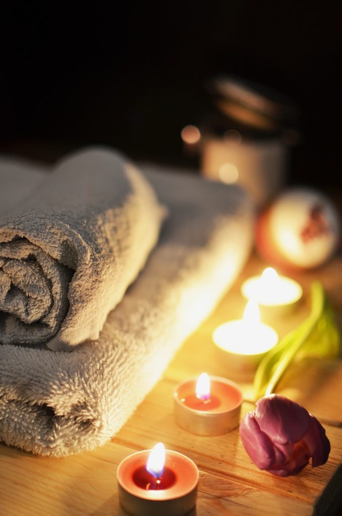 Candles with a towel and flowers in a spa-like setting. 