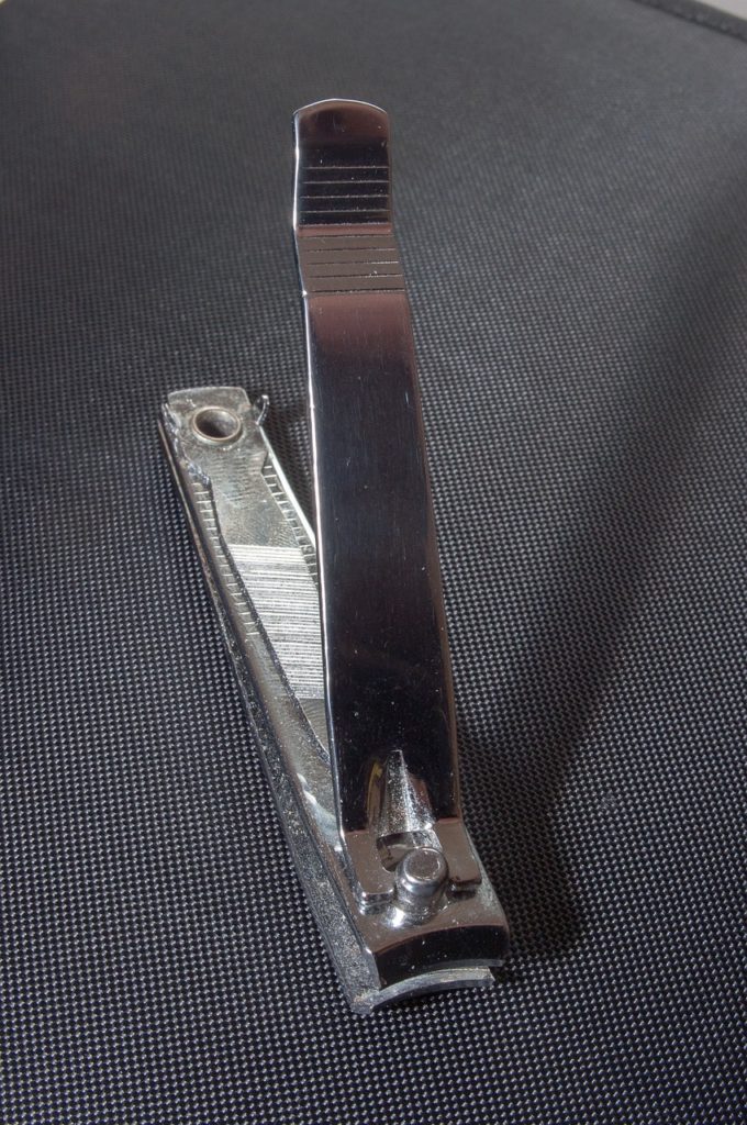 A close up of a nail clipper. Black textured background. 