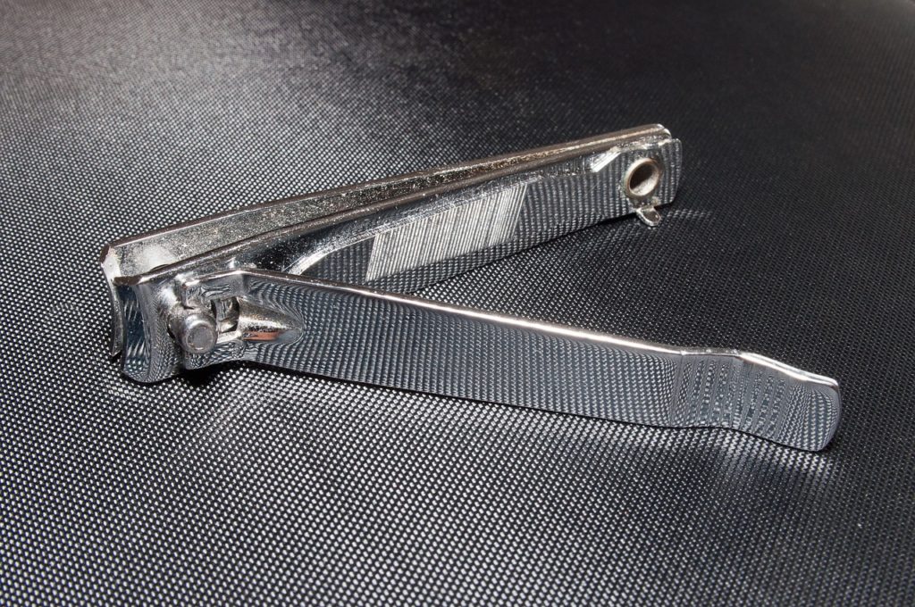 A close up of a nail clipper. Black textured background. 