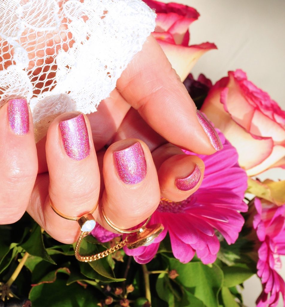A hand with a fresh pink manicure and flowers. 