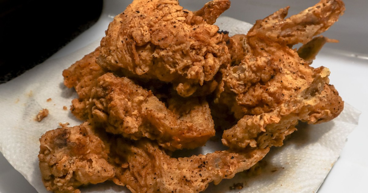 Golden brown fried chicken wings on a paper towel, showcasing a delicious, crispy texture.